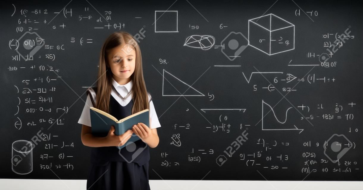 Uczeń czytający książkę i stojący przed tablicą z formułami geometrycznymi i matematycznymi