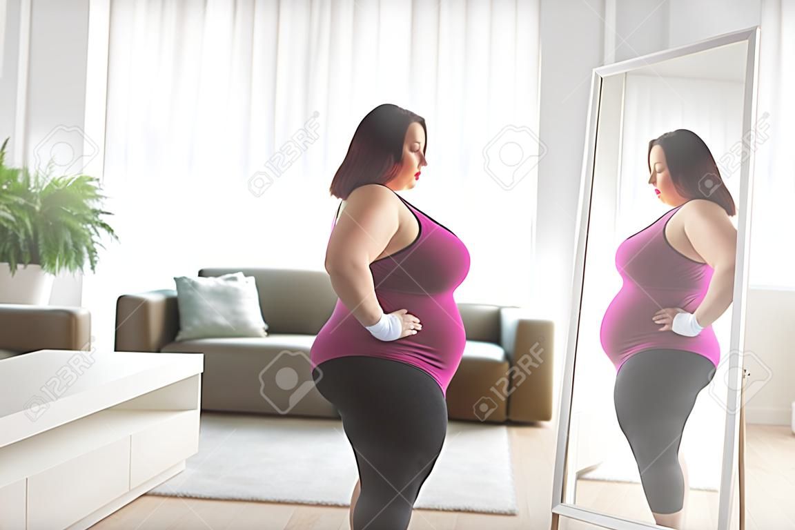 Plus size woman in sportswear standing in front of a mirror in a living room
