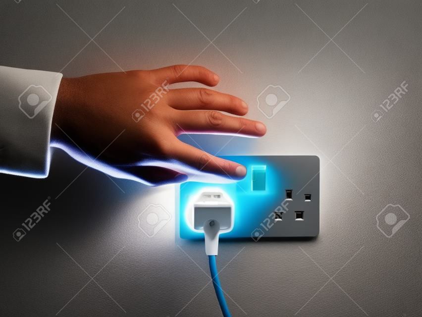 A male hand is pushing a switch on a wall socket