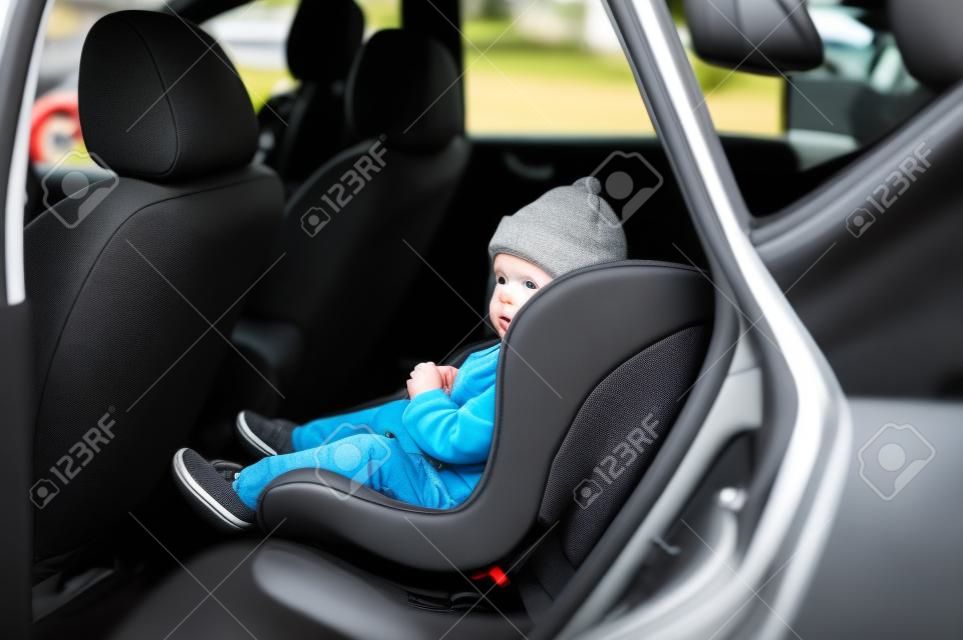 Un niño pequeño está sentado en su asiento de auto esperando para irse