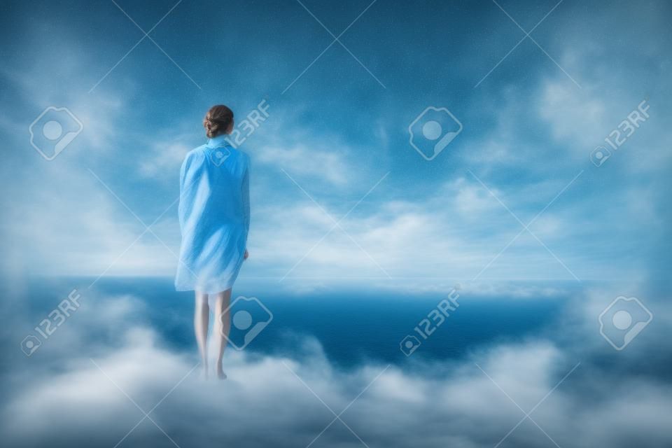 Ontop solitaria mujer pie de una colina en vista del océano.