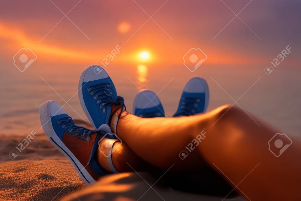 The legs of a guy and a girl in the evening on the beach.