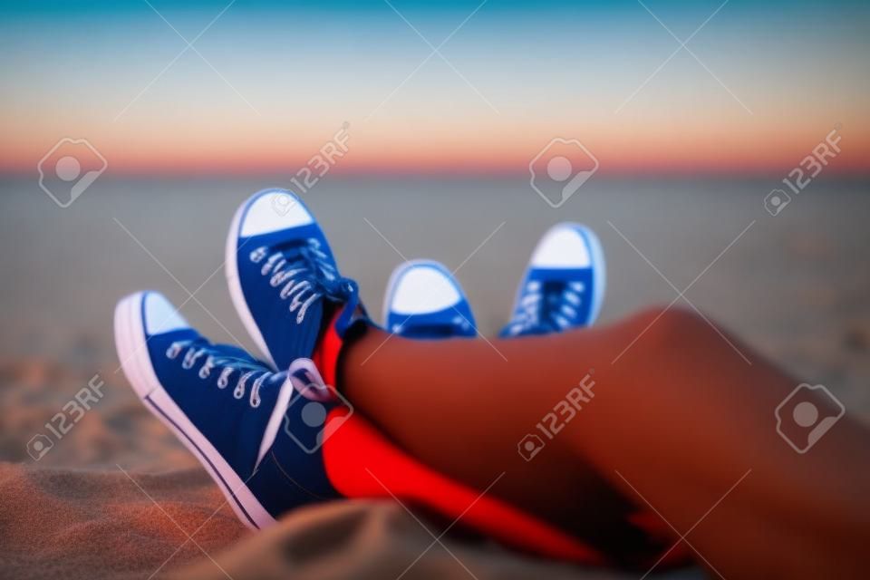As pernas de um cara e uma menina à noite na praia.