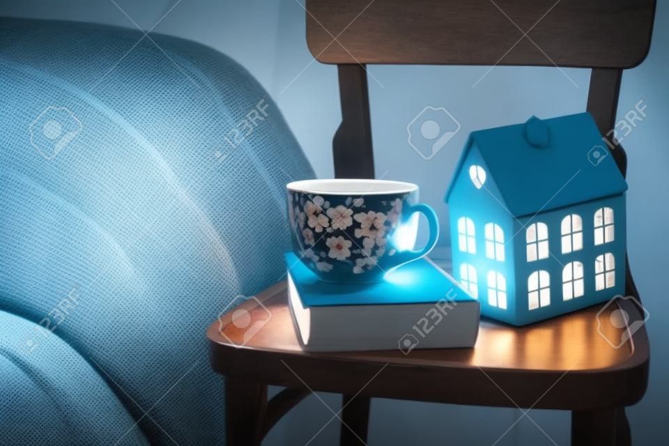 Cozy vintage bedroom interior closeup, cup of tea and a night light on a chair. Home interior decor with blue plaid and warm light.