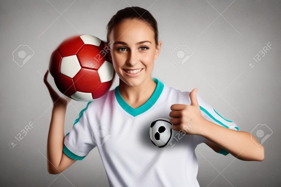 Uma menina no desgaste do esporte com futebol isolado no fundo branco