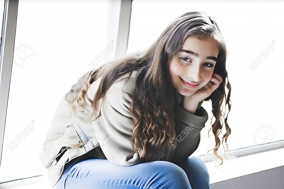 Teenager girl sitting on window