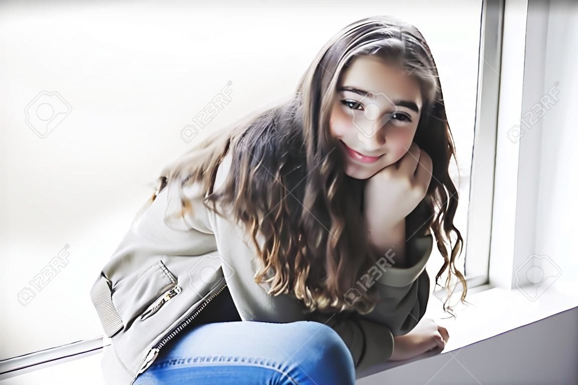 Teenager girl sitting on window