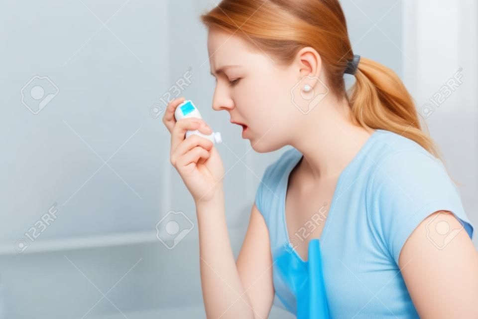 An Asthmatic using her inhaler because of breath difficulties