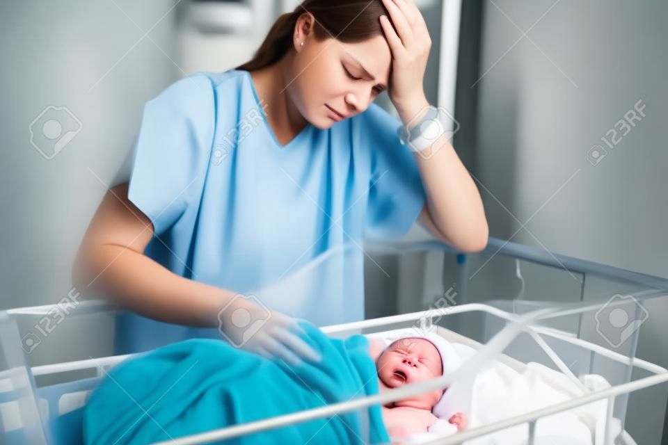 Smutna i przygnębiona matka z nowo narodzonym dzieckiem w szpitalu dzień po naturalnym porodzie
