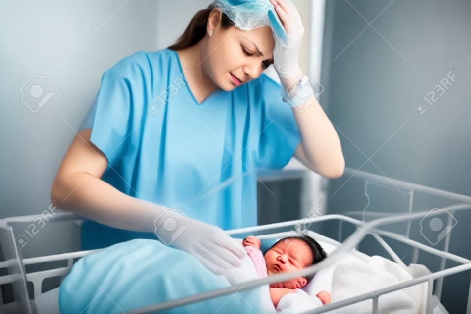 Smutna i przygnębiona matka z nowo narodzonym dzieckiem w szpitalu dzień po naturalnym porodzie