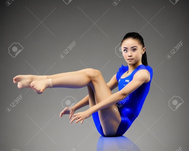 Гимнастка выполняет на полу акробатический элемент.
