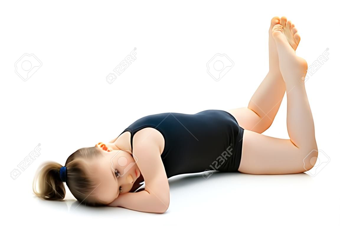 Маленькая гимнастка выполняет на полу акробатический элемент.