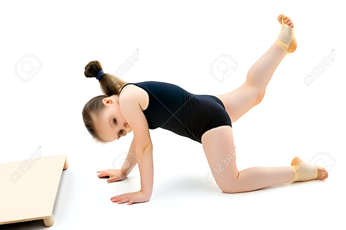 A pequena ginasta executa um elemento acrobático no chão.