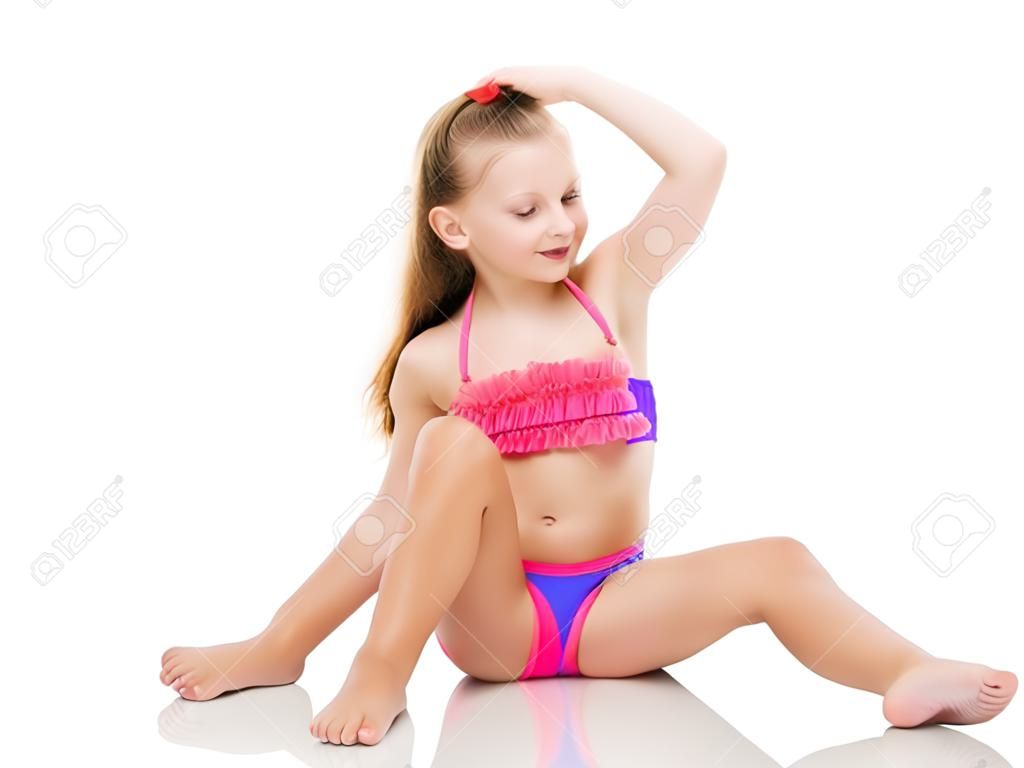 Schönes kleines Mädchen im Badeanzug sitzt auf dem Boden.