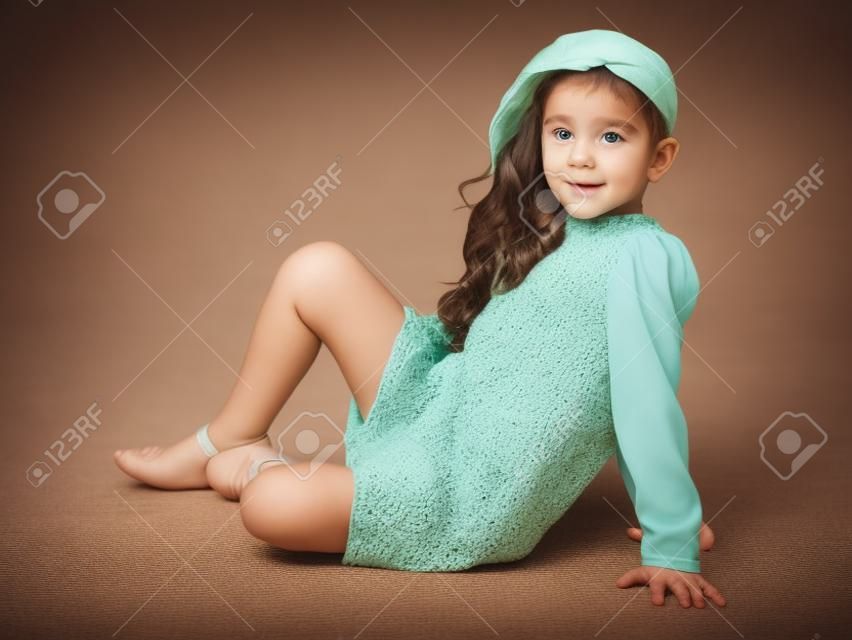 Mała dziewczynka siedzi na podłodze.