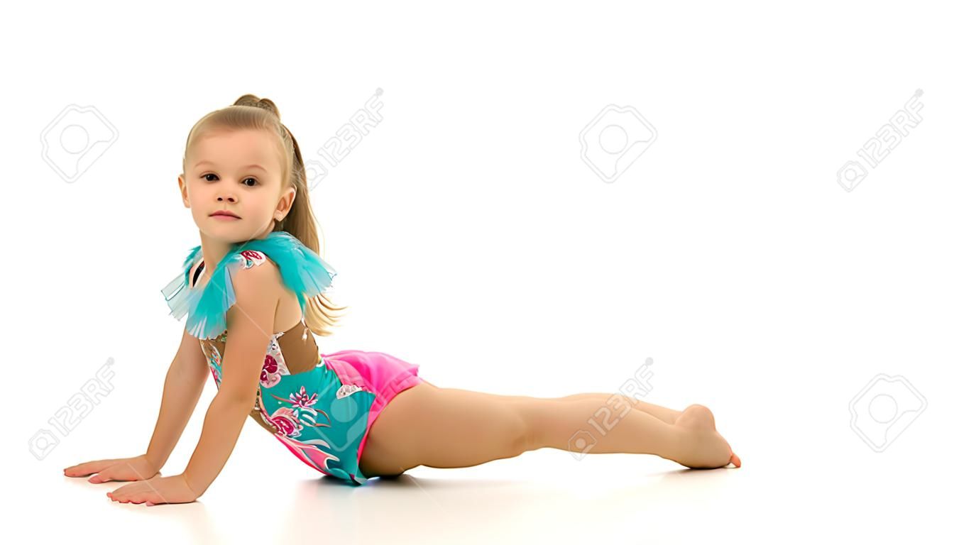 Encantadora niña haciendo ejercicios de gimnasia en el estudio sobre un fondo blanco.