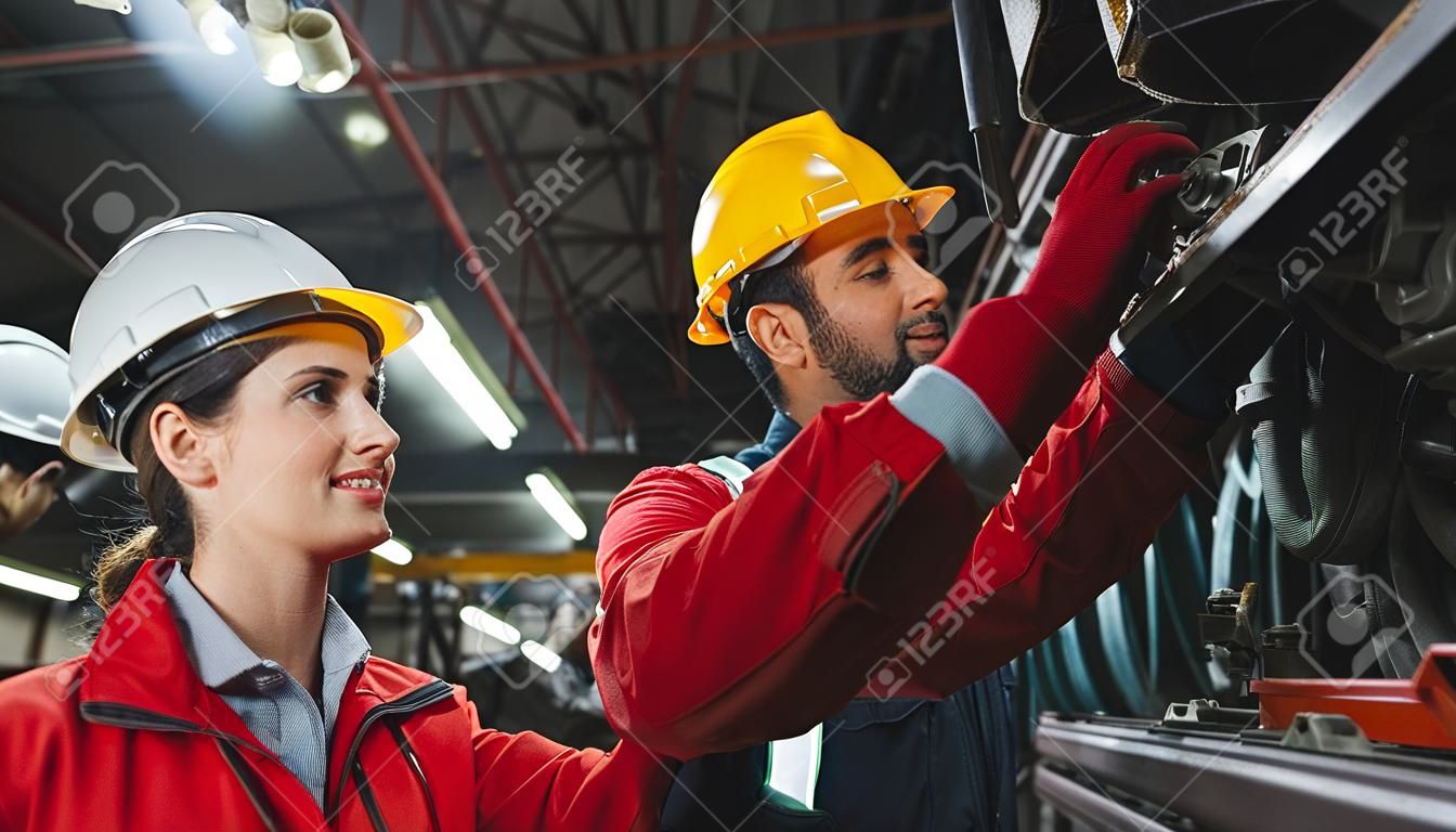 Female engineer and worker checking equipment in factory for repair