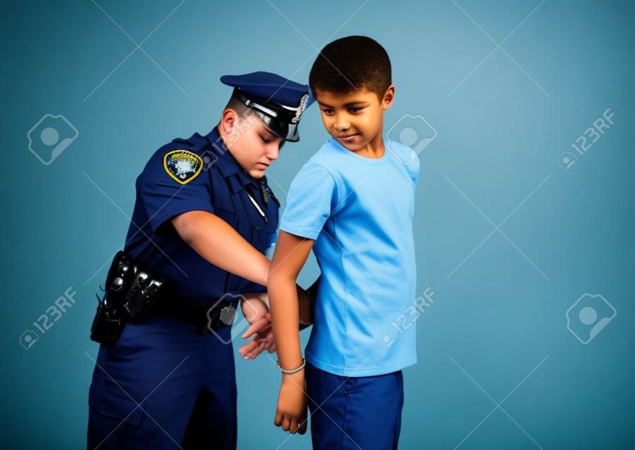 Un policier arrête et menottes un jeune malfaiteur pour adolescents mâle.
