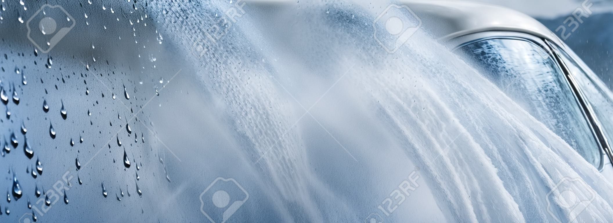 Abstract carwash banner, focus only on drops of water, jet spraying to car out of focus, toned in light blue color.