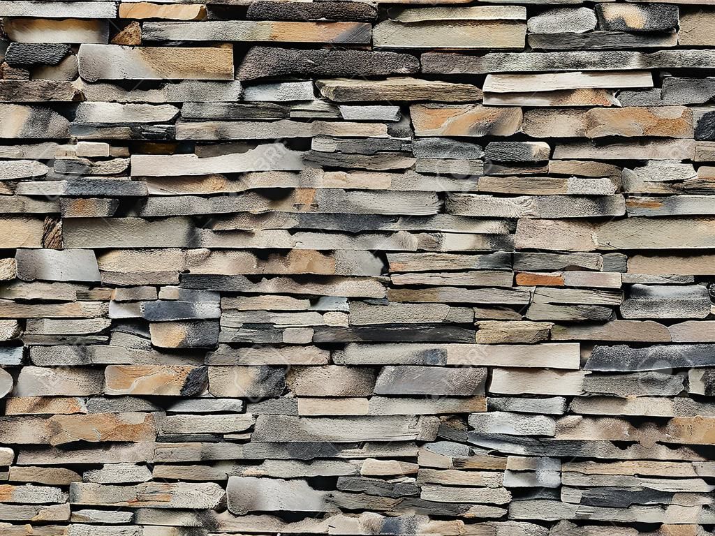 Muro a secco composto da sottili sassi orizzontali. I colori sono sfumature di marrone e grigio. Sfondo e consistenza