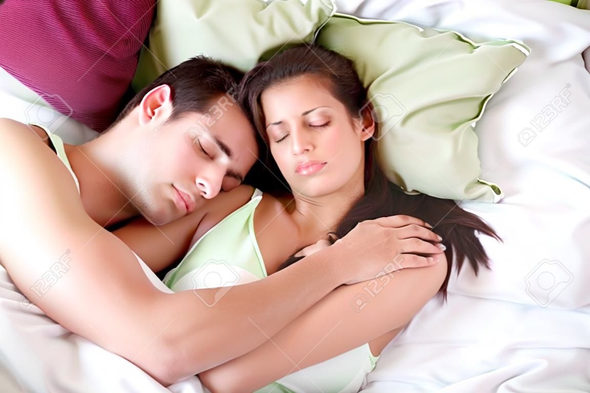 Embrassant jeune couple dormir sur le lit