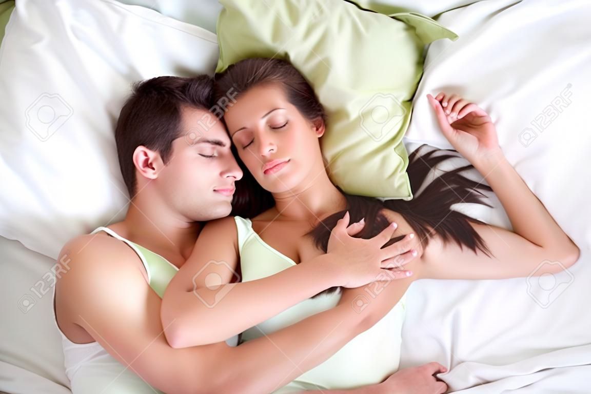 Abrazando a dormir joven pareja en la cama