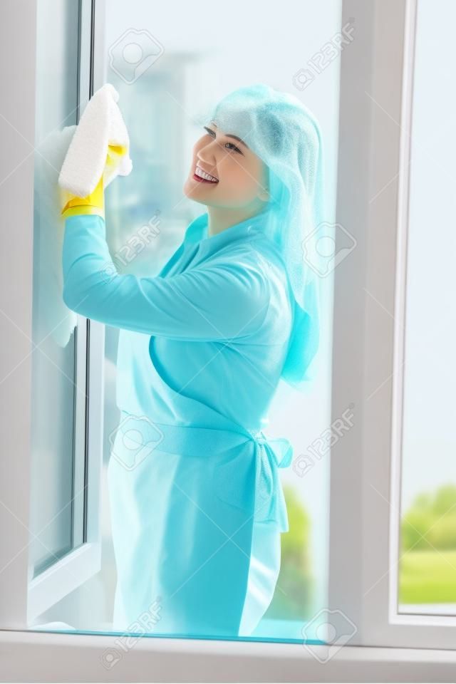 Huisvrouw schoon raam glas en maak voorjaar reiniging