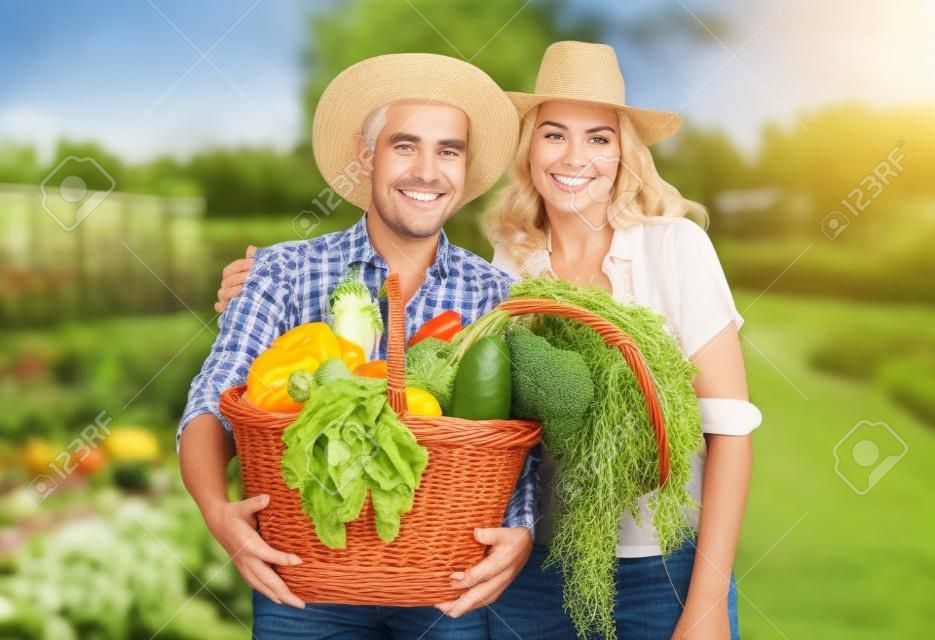 Les agriculteurs couple dans le jardin avec un panier plein de légumes
