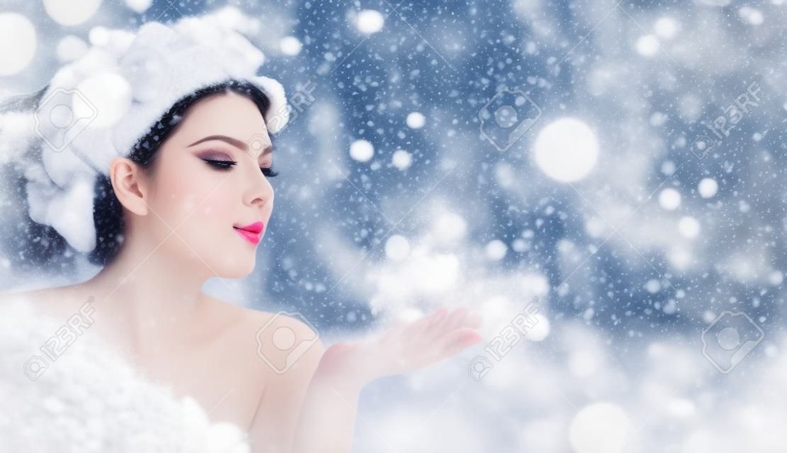 Piękna zimowa kobieta dmuchająca w magiczny proszek