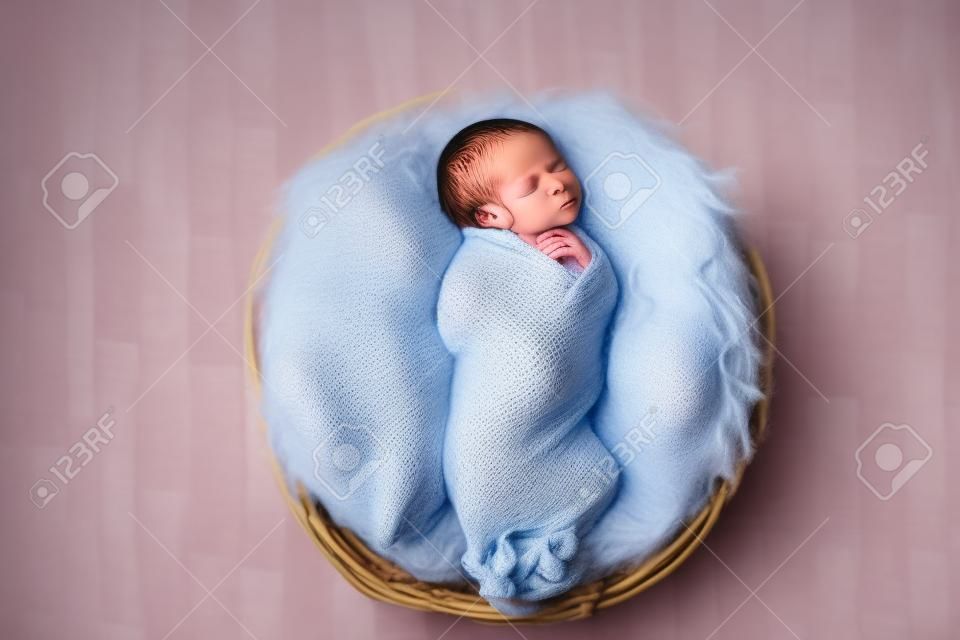 Little newborn baby sleeping in wooden basket on fluffy blanket, new youngest member of the family
