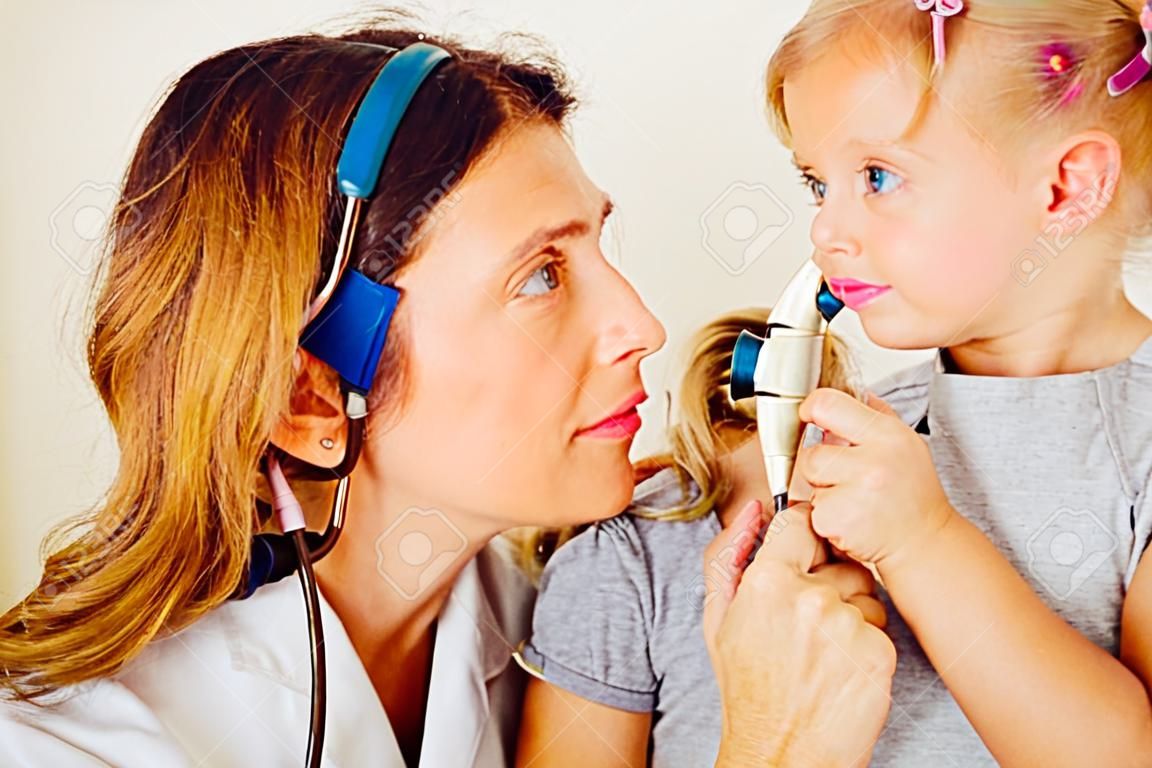 작은 girl`s 귀를 검사하는 소아과 의사.