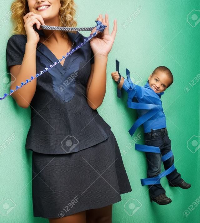 Garoto jovem amarrado à parede com fita adesiva, para que a mãe possa relaxar e ter uma conversa por telefone