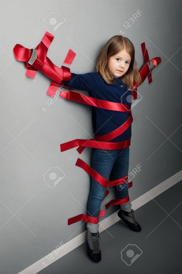 Junges Mädchen gefesselt an der Wand mit Klebeband