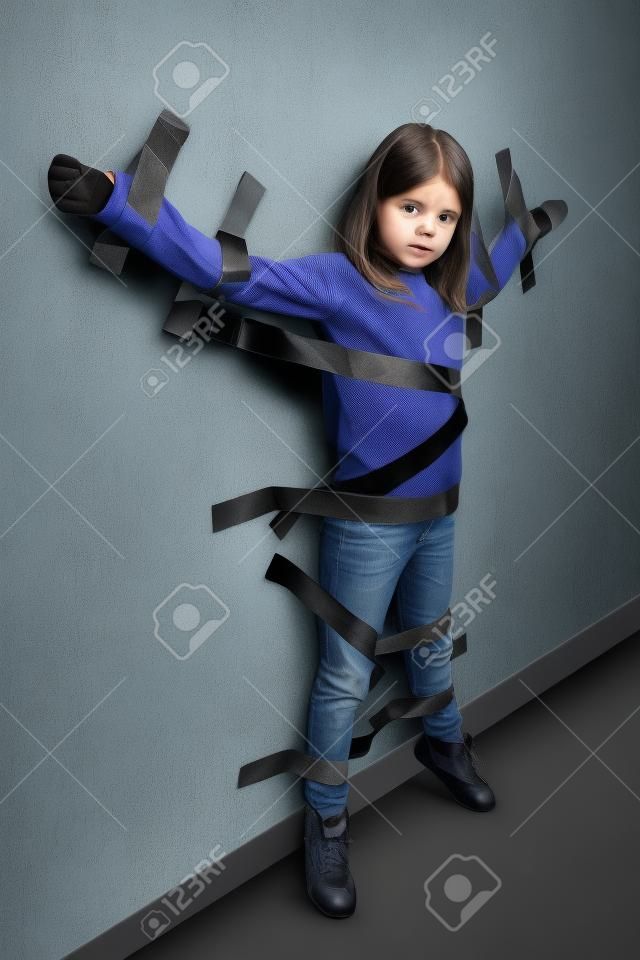 Junges Mädchen gefesselt an der Wand mit Klebeband
