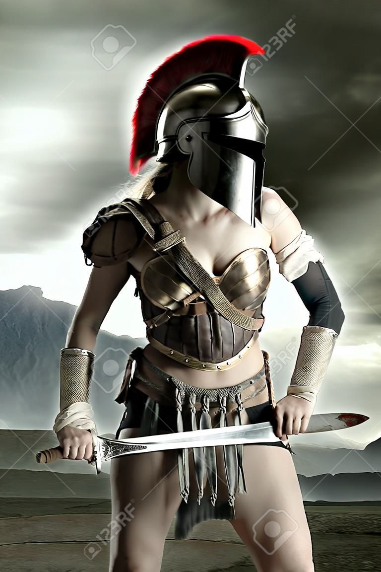 Antica donna guerriera o gladiatore in posa all'aperto con spada ed elmo