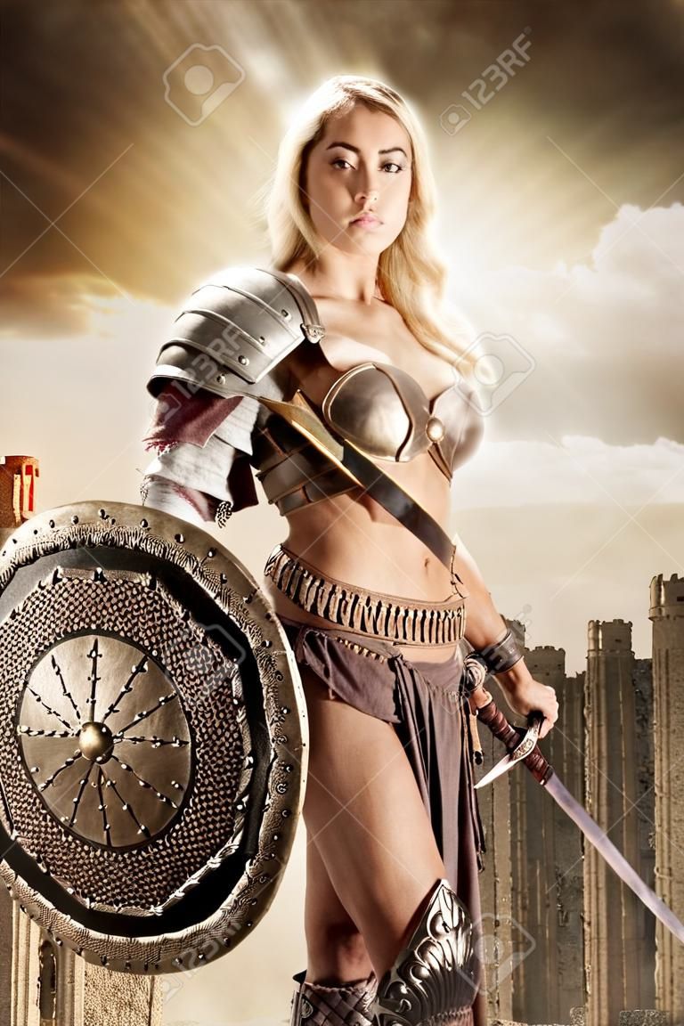 Mujer guerrera antigua o Gladiador posando al aire libre con espada y escudo