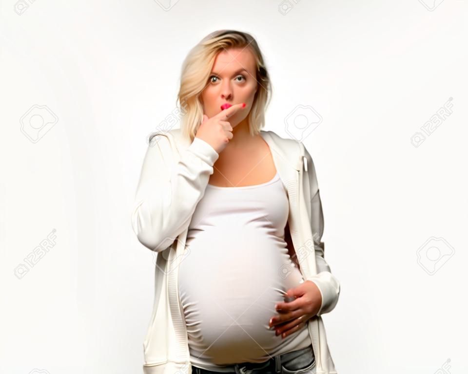 Schwangere blonde Frau mit weißem Sweatshirt, die ein Zeichen des Schließens des Mundes und der Schweigegeste auf isoliertem grauem Hintergrund zeigt