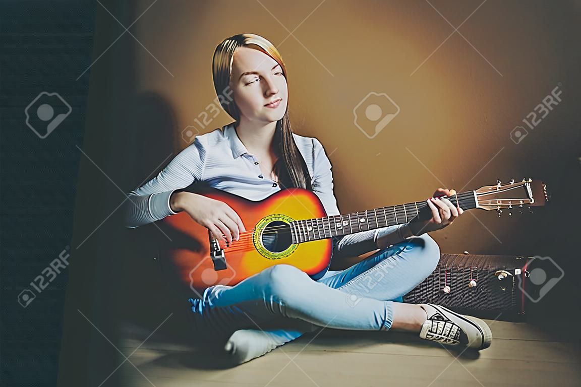 Stay Home Stay Safe. Young woman sitting in room on floor and playing guitar at home. Teen girl learning to play song and writing music. Hobby lifestyle relax Instrument leisure education concept