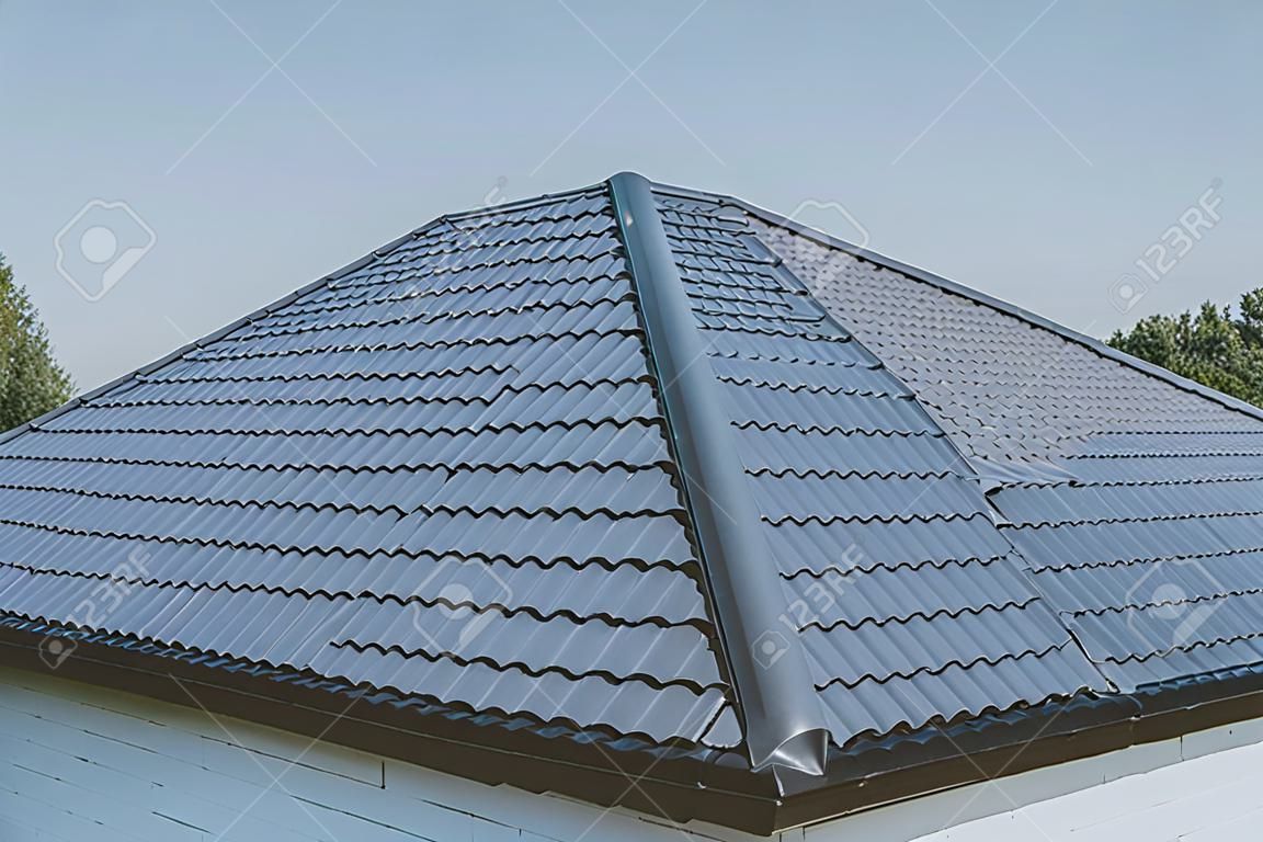 Modern roof made of metal. Gray-blue metal roof tiles on the roof of the house. Corrugated metal roof and metal roofing.