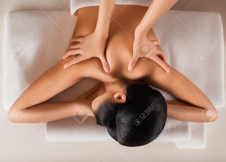 Asian woman enjoying a back massage at a spa centre.