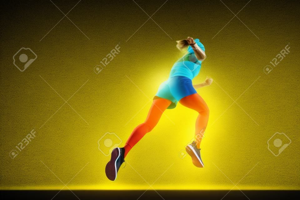 Back view. Sportive muscled woman, professional runner running away isolated on yellow background in neon light. Sport, fitness, competition, speed and active lifestyle. Copy space for ad. Sunset
