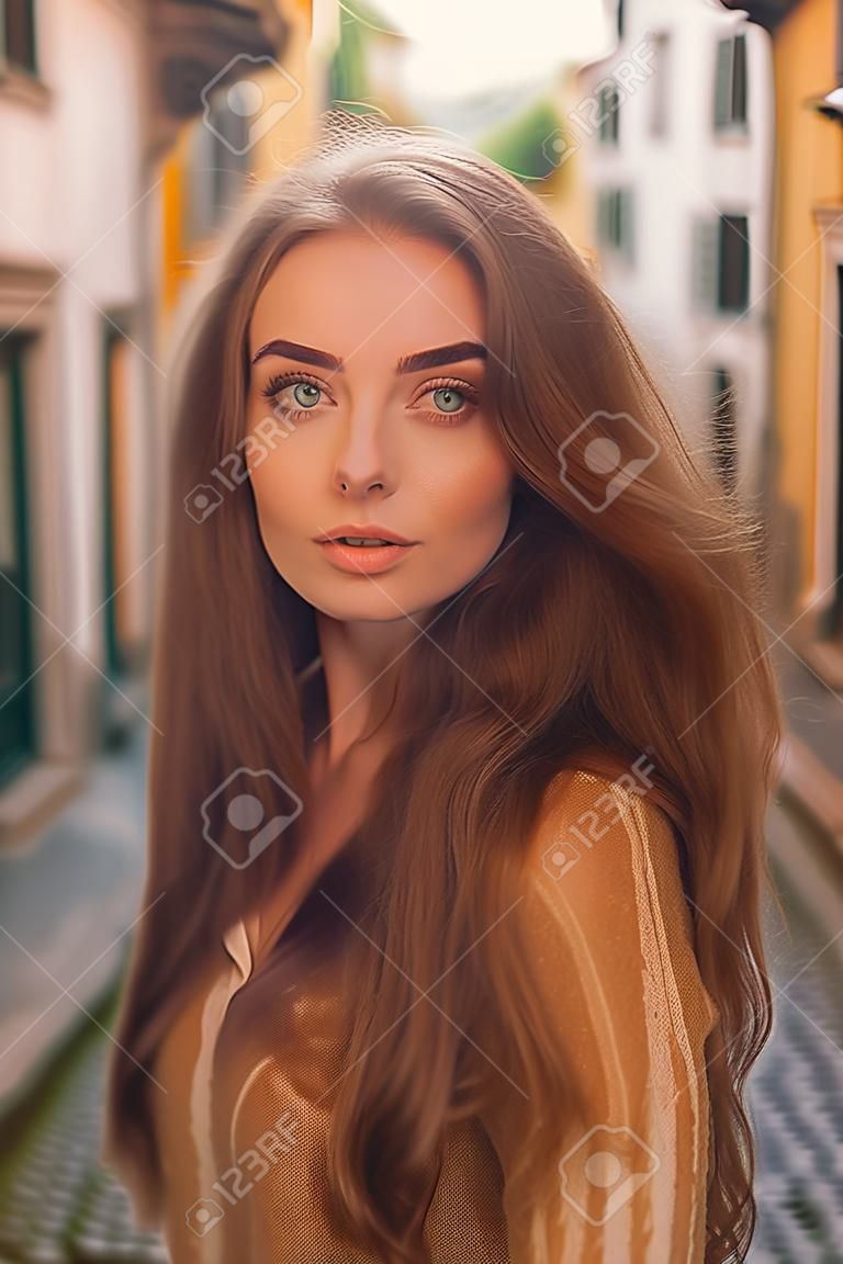 Portrait of beautiful young woman with long hair in the old town.