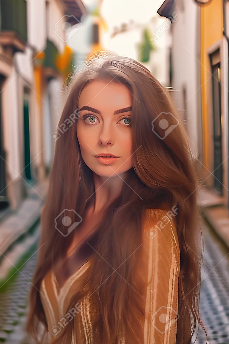 Portrait of beautiful young woman with long hair in the old town.