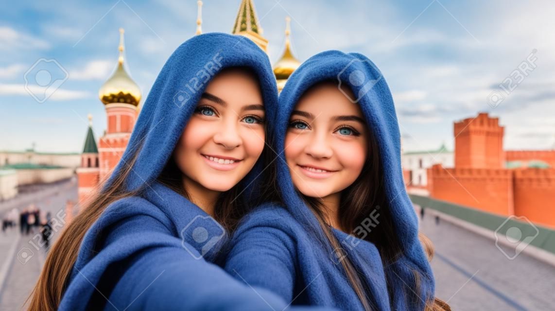 Two beautiful young girls make selfie on the background of the Moscow Kremlin