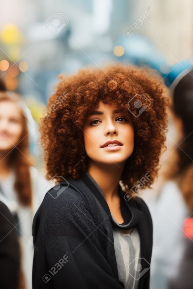 Portrait of a beautiful young woman with curly hair on the street