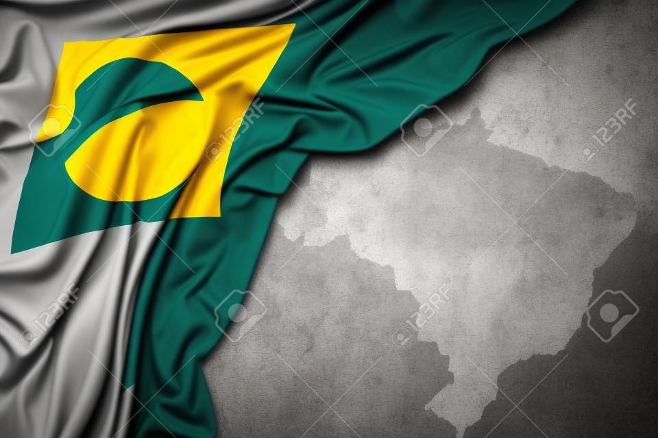 waving colorful national flag of brazil on a gray map background.