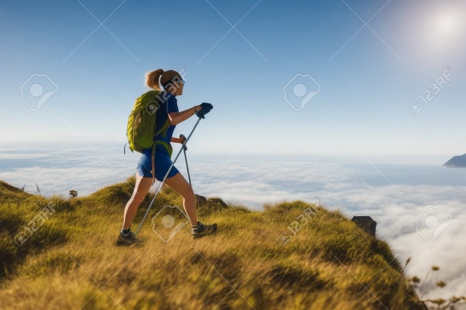 piernas de excursionista de mujer senderismo en sendero de montaña junto al mar