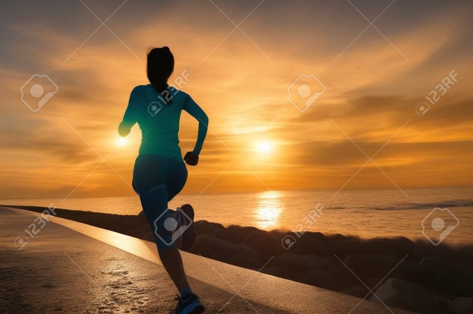 ランナーの選手が海辺で実行しています。女性フィットネス シルエット日の出ジョギング トレーニング ウェルネスのコンセプトです。