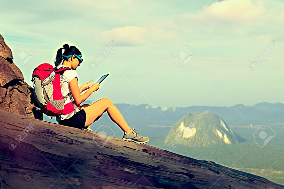vrouw wandelaar gebruik digitale tablet bij zonsondergang berg piek klif