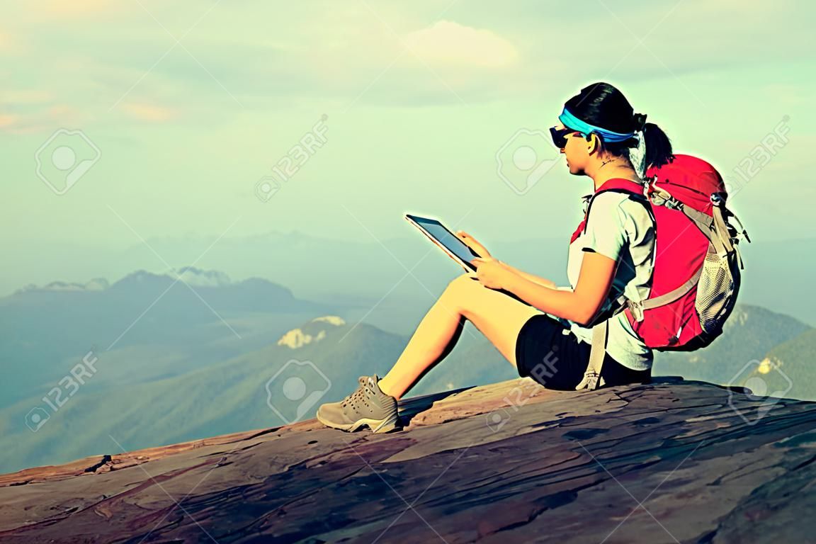 vrouw wandelaar gebruik digitale tablet bij zonsondergang berg piek klif